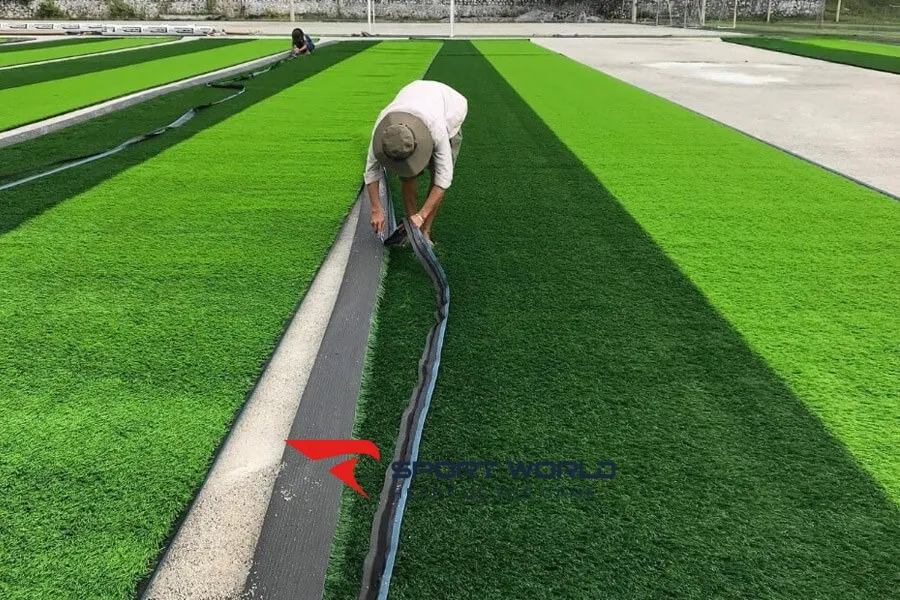 Trải thảm cỏ nh&acirc;n tạo s&acirc;n b&oacute;ng